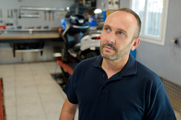 Obraz premium contemplative motorcycle mechanic in his garage