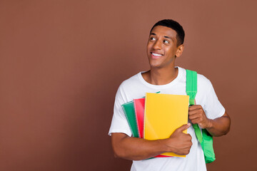 Photo of good millennial brunet guy look empty space hold copybook wear white t-shirt isolated on brown color background