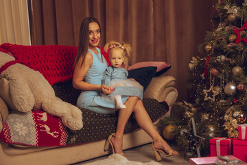 Beautiful young mom with little baby girl celebrate Christmas and New year