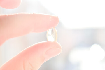Women's hand with Vitamin D capsule in Sunlight, Health concept
