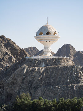 View to the Riyam Park monument dome through the palm leaves. Muscat, Oman.