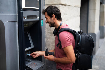 Young man withdrawing money from credit card. Man typing pin code on keypad of ATM mashine.