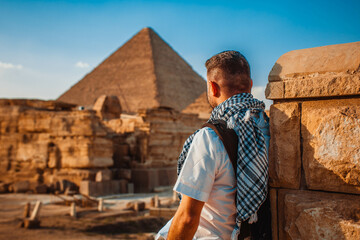 A tourist man stands with his back to the camera and looks at the pyramids. Meditation near the pyramids in Cairo, Egypt
 - obrazy, fototapety, plakaty