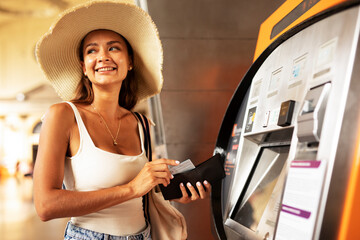 Fototapeta na wymiar Happy smiling young woman withdrawing money from credit card. Young woman using ATM mashine.