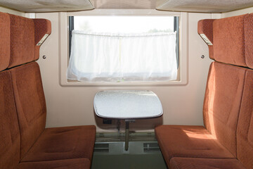 Soft sofas with high backs in the compartment of a railway train.