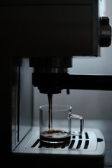 Coffee drips from the holder into a transparent glass mug