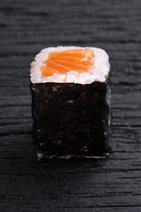 Roll of salmon on a wooden black