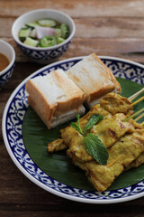 Local Thai food pork satay with oeanut dipping sauce isolated in wood background