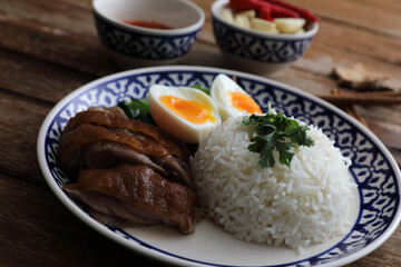 Local Thai food stewed pork leg on rice isolated in wood background