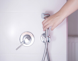 A woman's hand takes a hygienic shower for washing and care of intimate places, bidet. Close-up