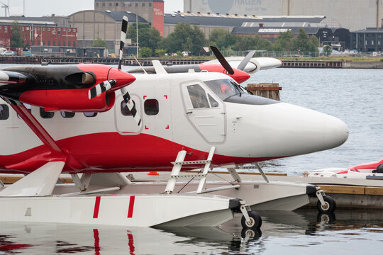 red and white floatplane next to a pier