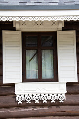 Fototapeta na wymiar Beautiful carved window shutters in a log wooden house. Rural country house, close-up