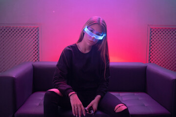 Futuristic neon glasses glow in the eyes of a young woman.
