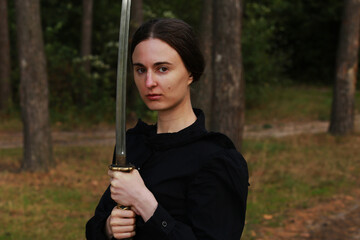 Woman in black classic clothes with katana sword in the forest