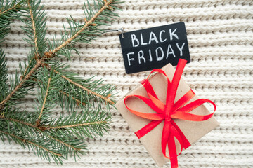 Black Friday big sale promotional sign on cozy winter background with fir branches and gift. Special discount Christmas offer. Advertising message. Top view. Holiday shopping. 