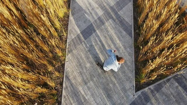 Active breakdancing on the street road. Aerial photography of dance against the background of street tiles and wheat. Windy autumn weather