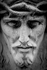 Fragment of an antique statue of Jesus Christ crown of thorns. Close up tears on face as symbol of pain, death and resurrection.