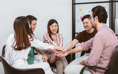 Group of Asian teamwork businesspeople making high five with togetherness or tag their hands with happiness and confidence after getting success on their projects and goal achievement.