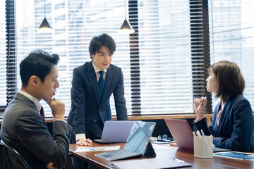 ノートパソコンで会議をする３人の男女のビジネスマン