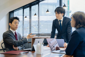 ノートパソコンで会議をする３人の男女のビジネスマン