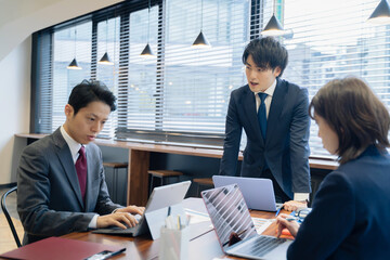 ノートパソコンで会議をする３人の男女のビジネスマン