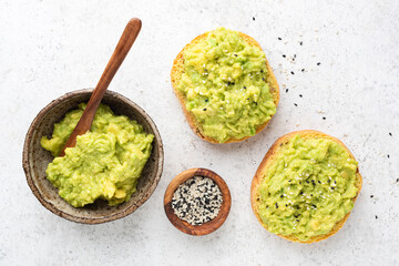 Mashed avocado on sesame bread toast, top view on grey concrete cement background. Healthy vegan food
