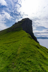 Fototapeta premium Beautiful aerial view of the Kallur Lighthouse in the Faroe Islands, and its massive cliffs, crags hikes and ocean views