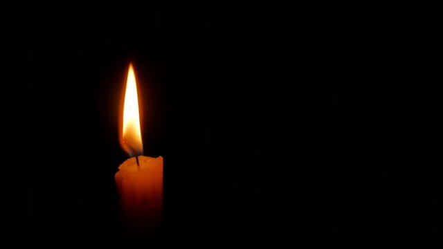 Extinguishing burning candle with fingers in the darkness. 