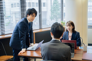ノートパソコンで会議をする３人の男女のビジネスマン