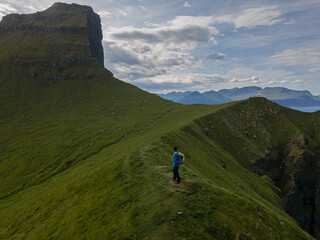 Fototapeta premium Beautiful aerial view of the Kallur Lighthouse in the Faroe Islands, and its massive cliffs, crags hikes and ocean views