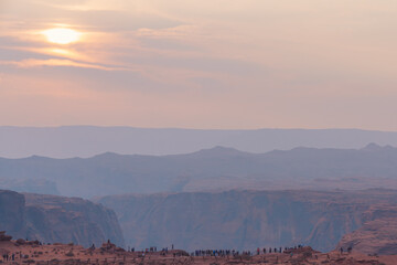 Obraz premium Scenic landscape. Sunset in desert with mountains, cloudy sky and silhouette of people enjoying the view