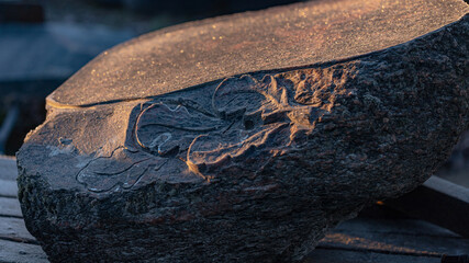 oak leaves carved in granite stone. Morning sunrise light and early hour frost