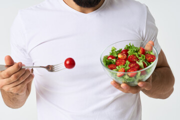 a man in a white t-shirt in a plate with salad a snack healthy food