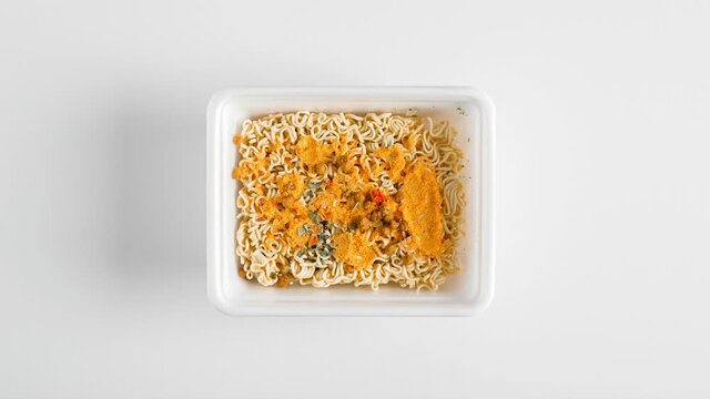 Chinese instant noodles animation video. Stop motion food. Top view box with noodles on white table, brewing with boiling water and leaving frame
