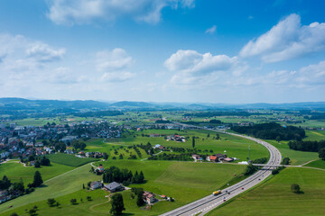 Obraz premium Panorama aerial view of the green Swiss hills on a summers day with blue skies.