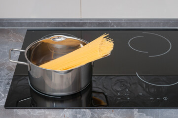 Dry spaghetti  in stainless saucepan on electric stove in a kitchen