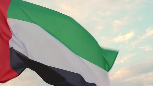 Flag waving against the sky with clouds, the national symbol of the United Arab Emirates. National Day and UAE Flag Day concept
