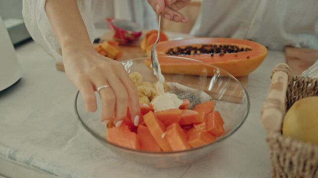 Young happy active married couple dancing laughing together cooking meals at home, carefree joyful husband and wife have fun cooking healthy breakfast food in boho styled kitchen