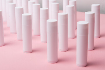 Lot of white plastic lip gloss tubes on pink background - obrazy, fototapety, plakaty