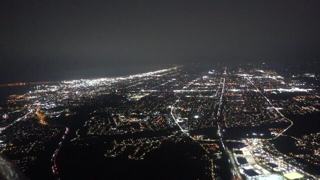 Airplane Aerial At Night Flying Over Major City With Heavy Fog Towards Lake Water