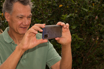 Senior man outside taking a photo with his smartphone 