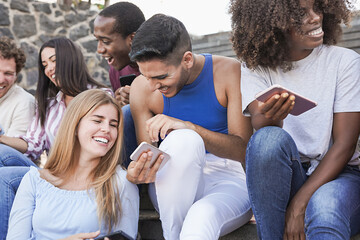Multiracial young friends enjoy day in the city while using mobile phone - Diverse millennial people and friendship concept