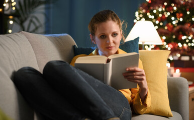 Woman lying on the sofa and reading a book at Christmas