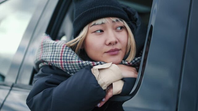 Positive Asian Woman Sitting In The Car And Looking At Window