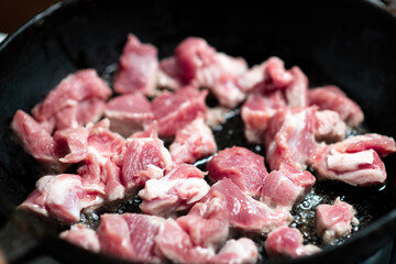 Raw meat goulash in a pan. The pieces of meat will be roasted.