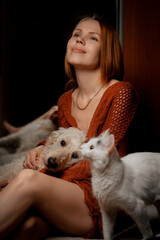 Obraz premium Attractive forty year old woman with a white cat and dog. Pets care concept.