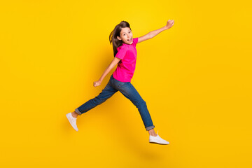 Fototapeta na wymiar Photo of funky hurry sporty girl jump run fast rush side wear pink t-shirt jeans shoes isolated yellow color background