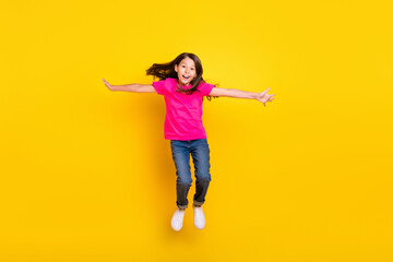 Fototapeta na wymiar Photo of little girl jump hands wings plane pose flight wear pink t-shirt jeans sneakers isolated yellow color background