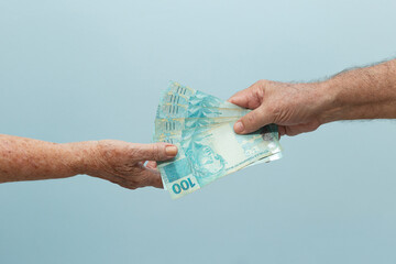 Mãos de idosos com dinheiro. Conceito de pagamento/recebimento. Uma pessoa entregando dinheiro para outra pessoa.