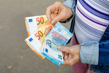 Hands of a senior citizen with euro notes, senior citizen counts her money - obrazy, fototapety, plakaty